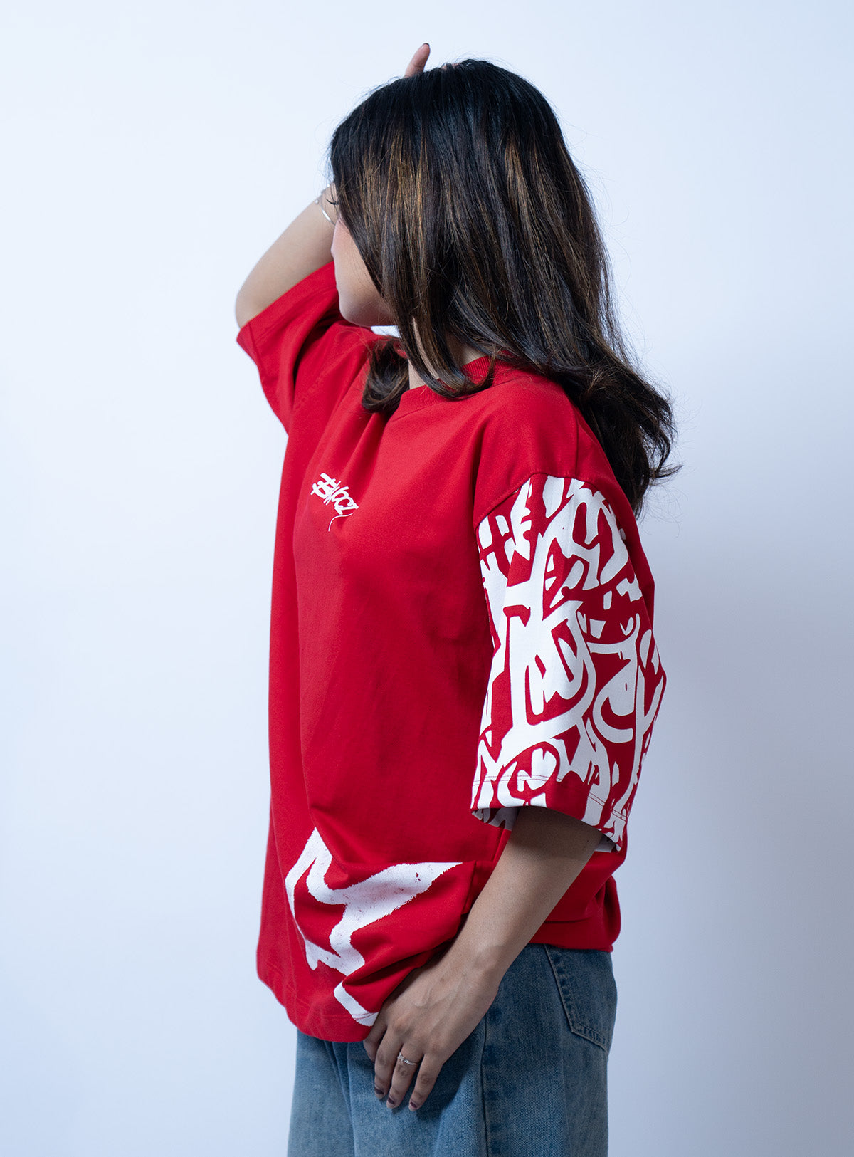 Side view image of a girl wearing red graffi tee from a street wear brand called Ballucci.