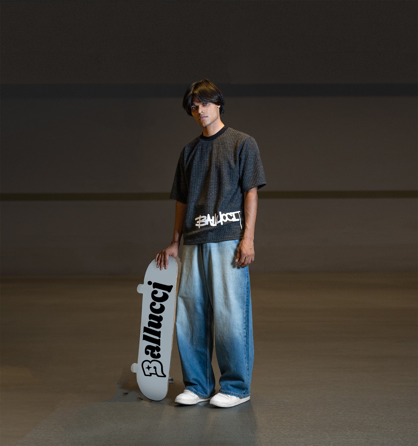 Image of a guy standing with a skateboard black tee from ballucci.